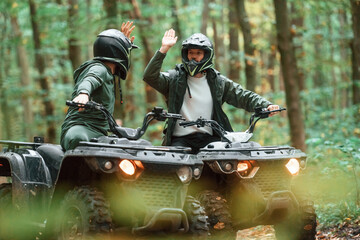 Giving high fives by the hands. Two male atv riders is in the forest together
