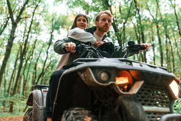 Close up view of another transport. Young couple riding a quad bike in the forest