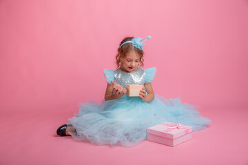 little girl sitting celebrating birthday on pink background, beautiful princess 