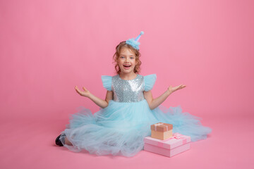 Obraz na płótnie Canvas little girl sitting celebrating birthday on pink background, beautiful princess 