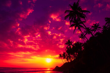 Coconut palm trees on tropical ocean coast at sunset with vivid colorful sky