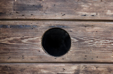 Un buco nero al centro di una vecchia porta di legno