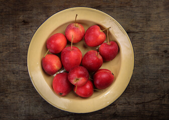 Small red Autumn Strawberry shaped Apple cut slice seed in enamel metal plate on rustic wooden background