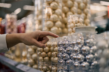 Woman's hand pointing to christmas balls in store

