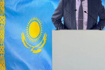 Tribune with microphone and man in suit on Kazakhstan flag background. Businessman and tribune on...