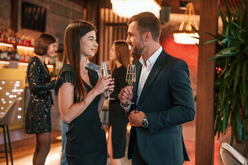 Man with woman is posing. Group of people in beautiful elegant clothes are celebrating New Year...
