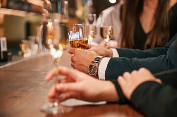 Close up view of hands with glasses. Group of people in beautiful elegant clothes are celebrating New Year indoors together