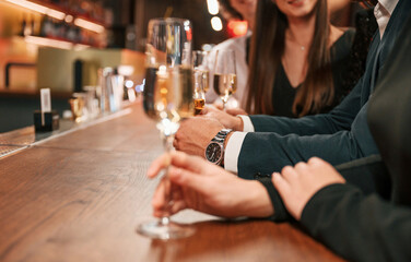 Close up view of hands with glasses. Group of people in beautiful elegant clothes are celebrating New Year indoors together