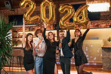 With 2024 numbers balloons. Group of people in beautiful elegant clothes are celebrating New Year...