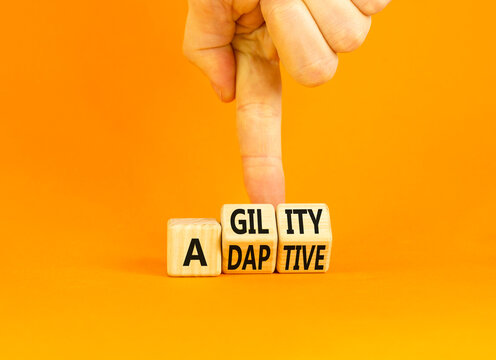Agility and adaptive symbol. Concept words Agility and Adaptive on wooden cubes. Beautiful orange table orange background. Businessman hand. Business agility and adaptive concept. Copy space.