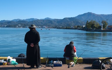 fishermen on the sea promenade, two people are filmed from the back looking at the sea
