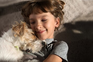 Happy child with a dog. Portrait of a girl with a pet. Jack Russell lying on her chest