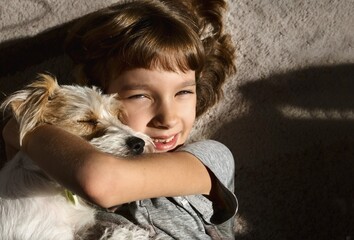 portrait of a female child with a dog fluffy jack russell on the floor and smile
