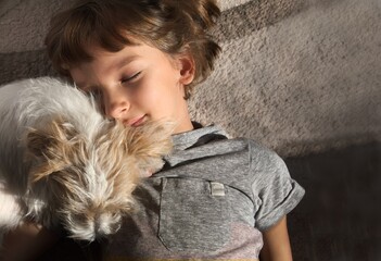 portrait of a female child with a dog fluffy jack russell on the floor with closed eyes