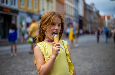 Beautiful blonde girl eats an ice cream in the street