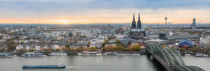 Naklejka premium Köln Panorama von der Stadt mit Innenstadt, Kölner Dom, Hauptbahnhof, Hohenzollernbrücke, Groß St. Martin, Fernsehturm, Rheinufer und Rhein in der untergehenden Sonne im Oktober 2022