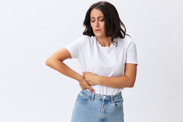 Woman pain during menstruation, abdominal pain appendicitis, age problems, early menopause, cystitis, a woman in a white t-shirt on a white background in jeans, copy space
