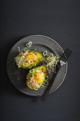 egg baked in avocado with spring onion and alfalfa sprouts