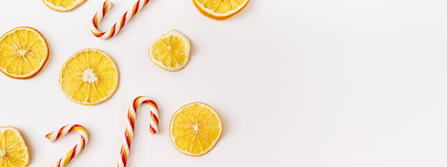 Christmas Banner. winter, new year composition. Slices of dry oranges and candies on white background. Food background. Flat lay, top view, copy space