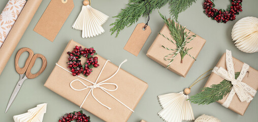 Christmas background with gift boxes and rolls of colored kraft wrapping paper. Xmas celebration, preparation for winter holidays. Festive mockup, top view, flatlay