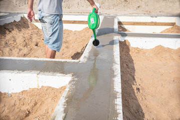 Concrete foundation for a new house A++, the man waters to prevent the foundation