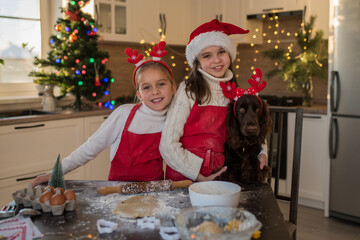 Happy girls with dog while making christmas cookies at home