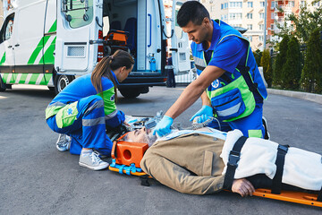 Ambulance paramedic with defibrillator performing cardiopulmonary resuscitation on cardiac patient...