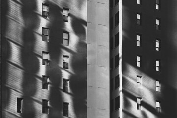 Black and white abstraction of sunlight reflecting on brick building façade with windows in shadow. Fine art photograph.