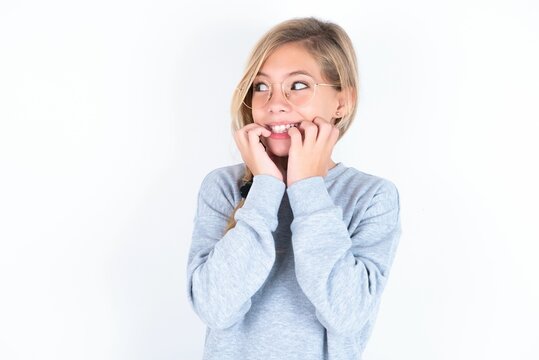 Terrified beautiful caucasian teen girl wearing gray sweater over white wall looks empty space home alone moonless night