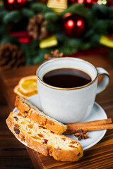 Pieces of stollen and a cup of coffee on the background of Christmas decor