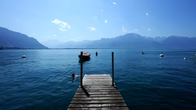 Beautiful Swiss pristine lake with mountains in background. Wooden pier deck in natural setting at Montreux Switzerland