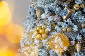 Close-up of a festively decorated outdoor Christmas tree with balls on a blurred sparkling fairy background. Defocused garland lights, bokeh effect.