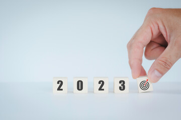 Hand putting wooden cube goal target New Year 2023 concept, mobile stick with new year 2023, business vision and horizontal size image.