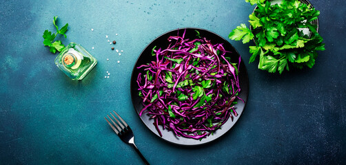 Healthy food salad with red cabbage, carrot, parsley and olive oil dressing on white kitchen table background, top view