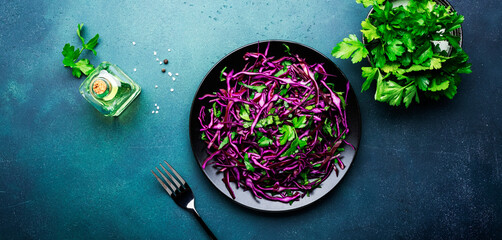 Healthy food salad with red cabbage, carrot, parsley and olive oil dressing on white kitchen table...