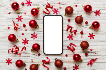 Christmas online shopping from home phone with blank white display top view. smart mobile with copy space on colored background with Christmas decorations balls,. Winter holidays sales background