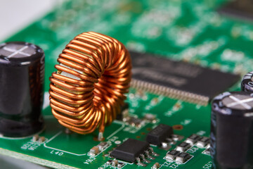 Orange inductor with copper wire on green printed circuit board detail