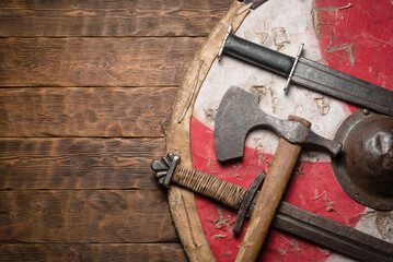 Old battle axe, swords and shield on the wooden table flat lay background with copy space.