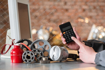 Worker is calculating the price of car spare parts with calculator concept. Car repair cost...
