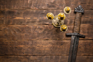 Knight sword and candle on the wooden flat lay table background with copy space.