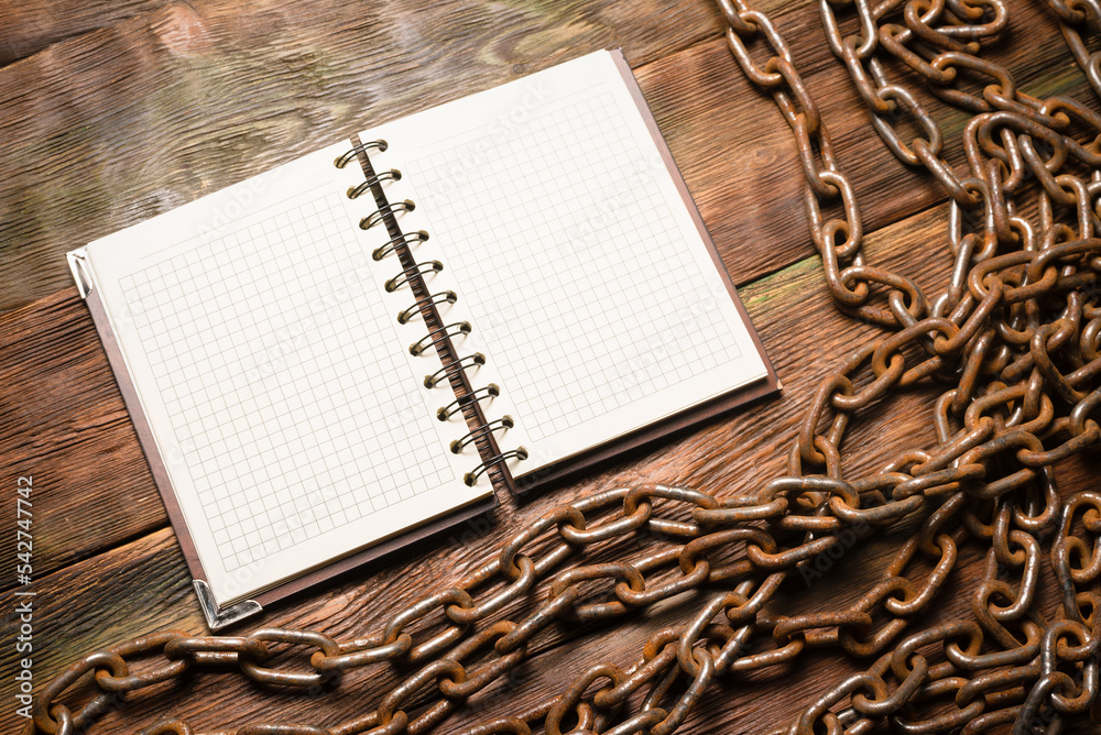 Wall mural open blank page notebook with copy space and old rusty iron chain on the wooden table background. to