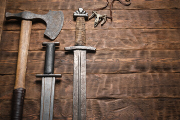 Ancient sword and axe on the brown wooden table flat lay background with copy space.
