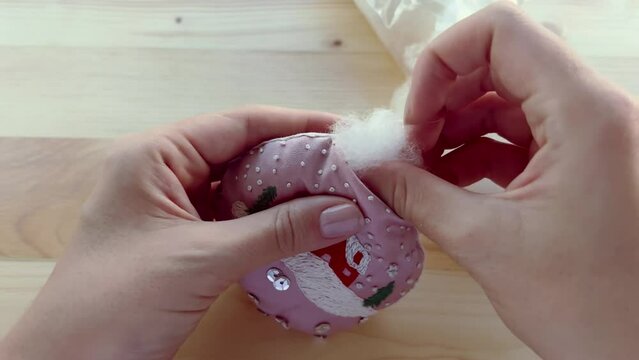 Christmas DIY. Flocking a festive decor toy with handmade embroidery using cotton fiber. Mounting a Christmas tree ornament with polyester batting. Film grain texture. Soft focus. Live camera. Blur.