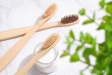 Many bamboo toothbrushes and white mineral toothpowder in container - kaolin powder or baking soda...