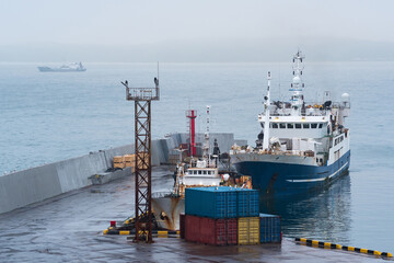 Naklejka premium fishing boat at the pier in the harbor on the shore of a cloudy sea