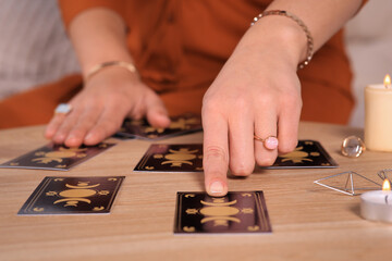Soothsayer predicting future with tarot cards at table indoors, closeup