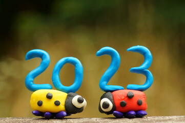 Two ladybugs and the number 2023 on a colored background. Calendar date. A festive event. Christmas and New Year.