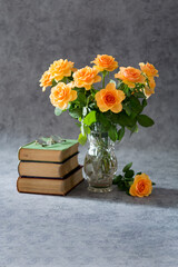 Bouquet of cream roses in a crystal vase, three books and glasses on grey background - 542755104