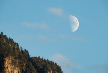 white moon next to swiss mountain