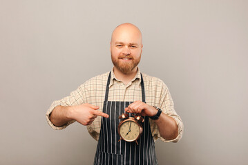 It is coffee time says a male barista while holding a vintage round alarm clock. Studio shot over...